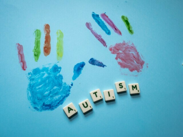 imagem de fundo azul com marca de mãos coloridas abaixo escrito autismo